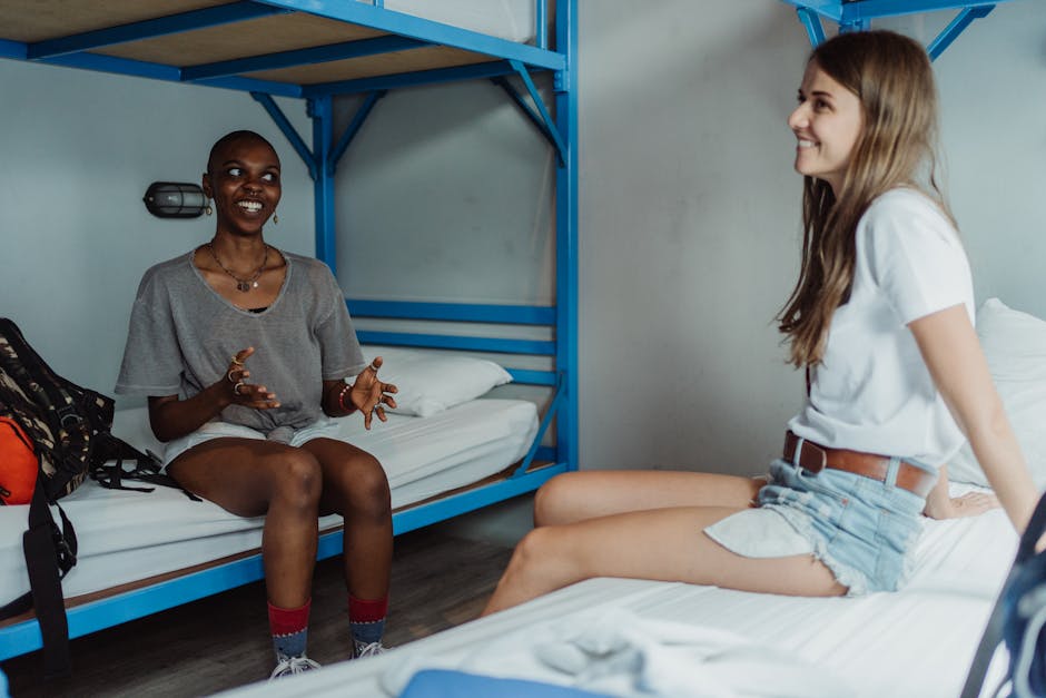 Friends chatting in a Brussels hostel common room with bunk beds and natural light