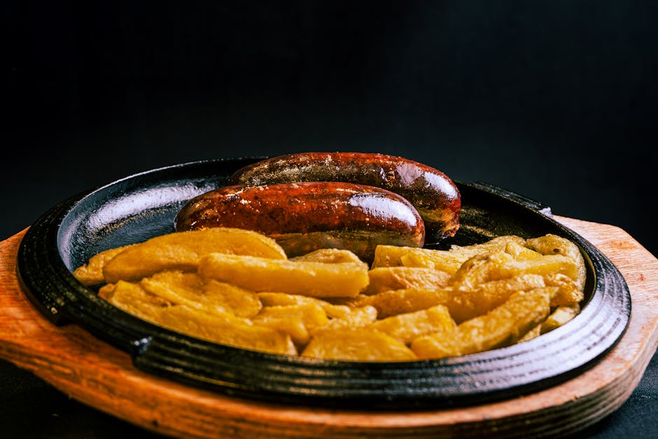 Traditional Belgian dishes Brussels — rustic grilled sausage and potatoes served hot on wooden sizzling plate
