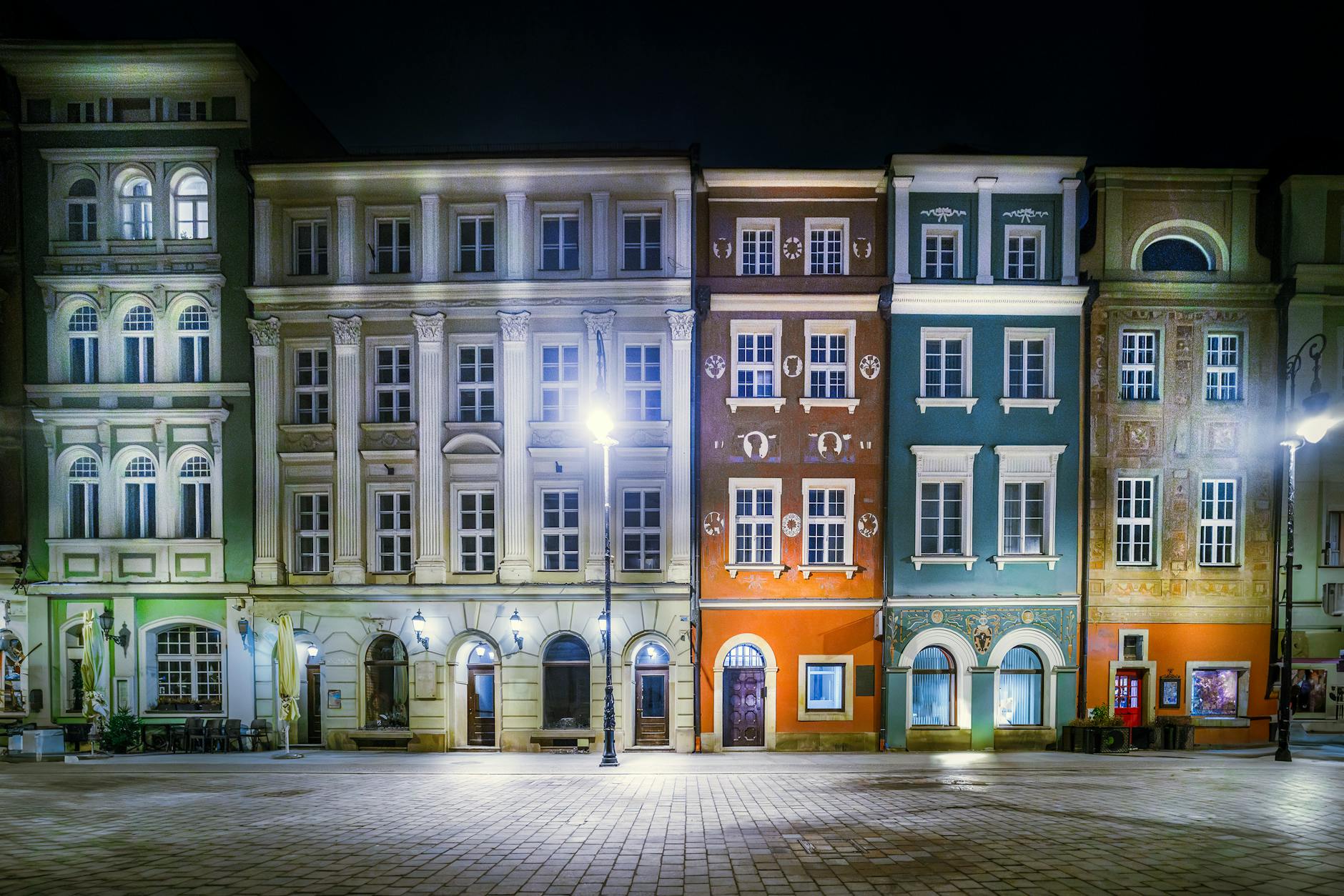 An illuminated European city square at night with historic buildings