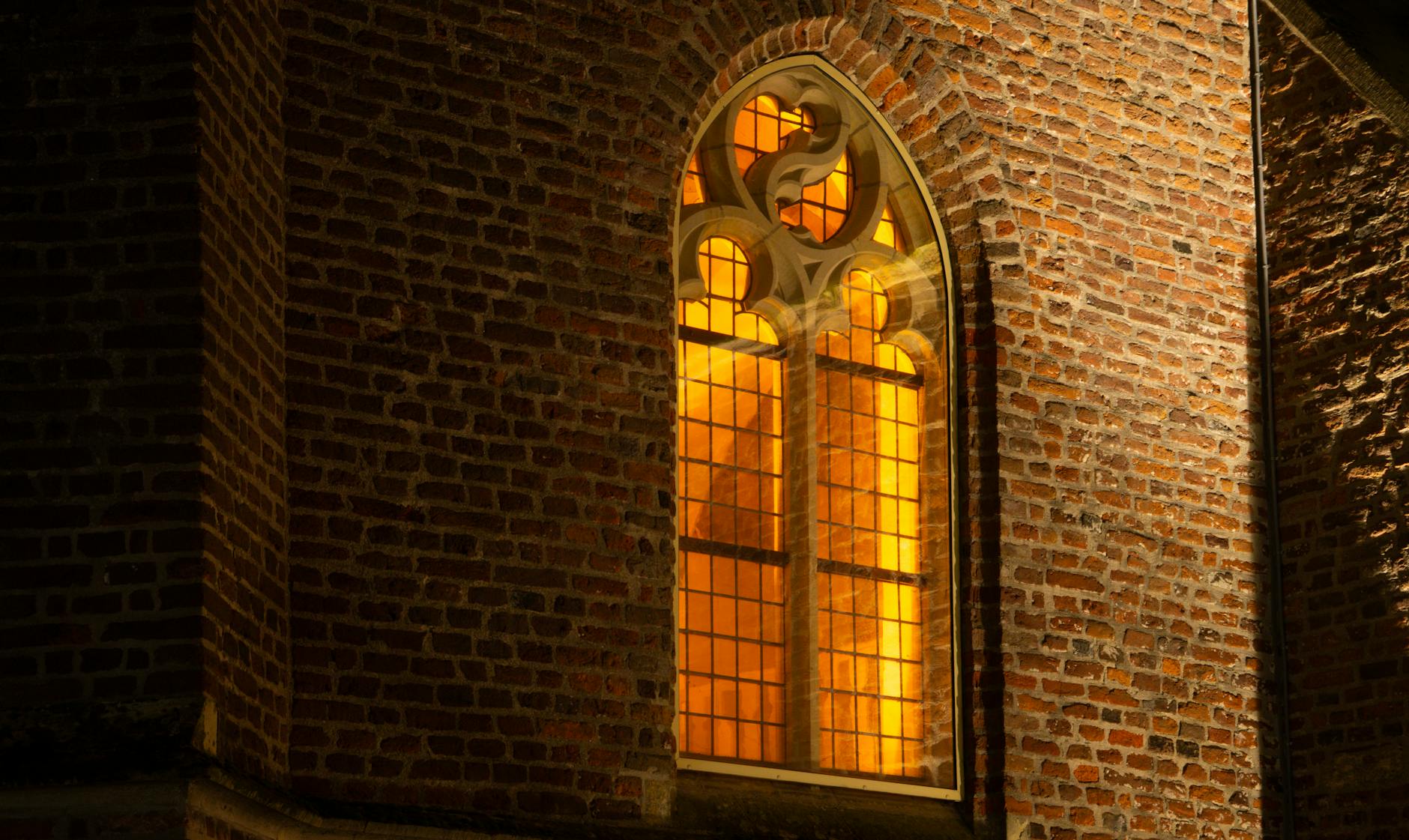 An illuminated Gothic church with stained glass glowing at night