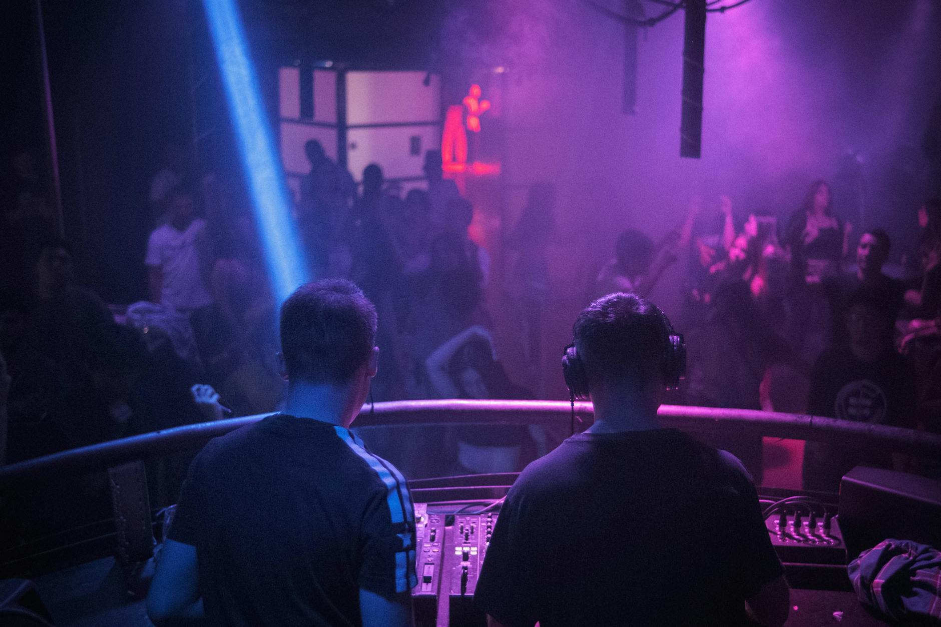 Crowded nightclub dance floor with atmospheric lighting and DJ booth