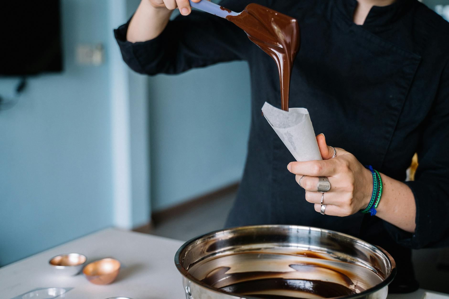 Hands crafting artisan chocolate pralines at a workshop