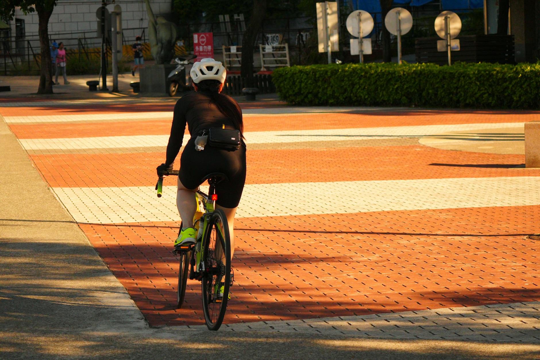 A cyclist riding along a tree-lined urban bike path