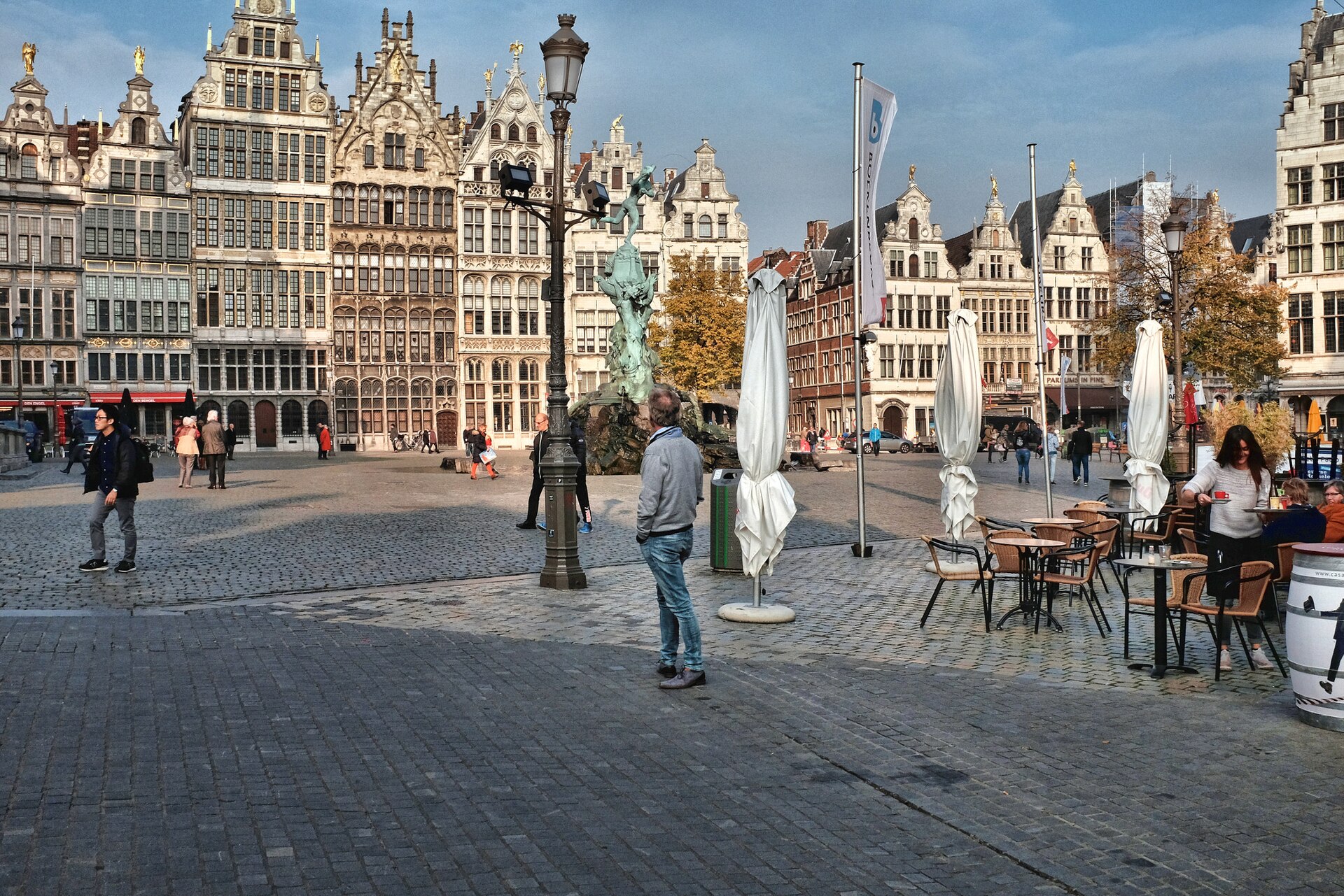 The Renaissance guild houses and Brabo fountain on the Grote Markt in Antwerp with café tables in the foreground