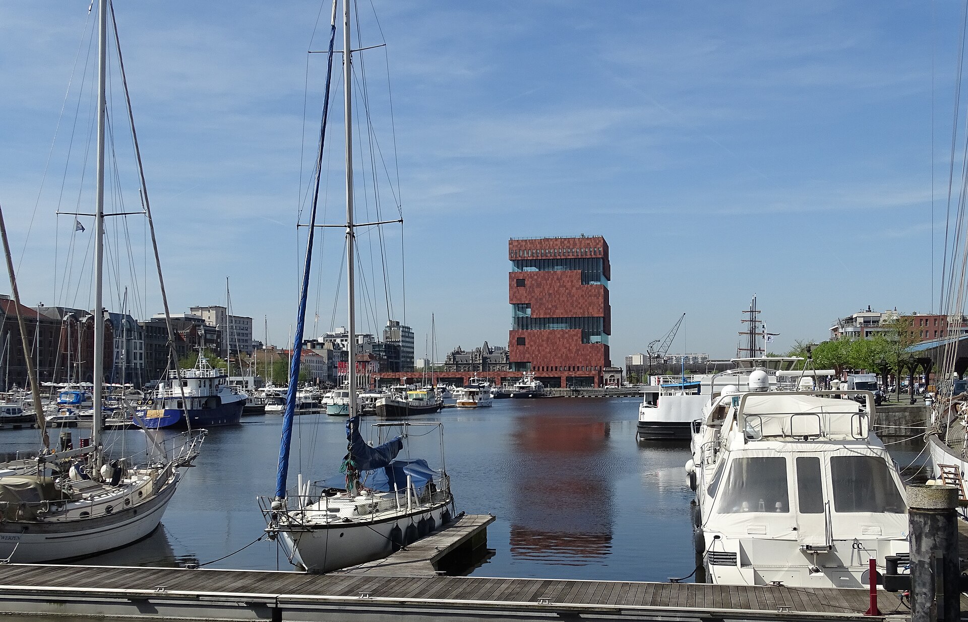 The red sandstone tower of the MAS museum in Antwerp seen across a marina full of moored yachts