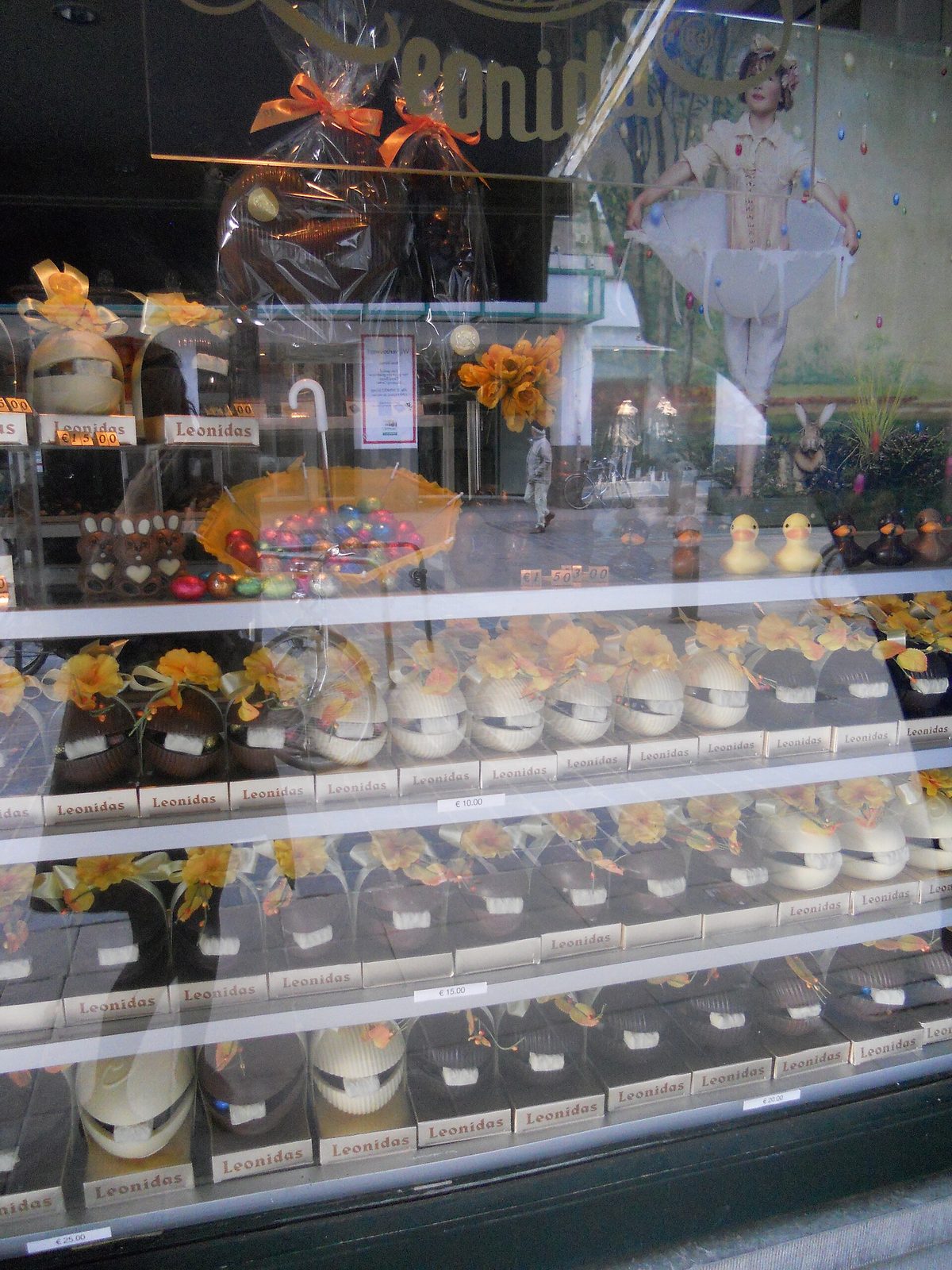 A Leonidas chocolate shop window filled with Easter eggs in white and dark chocolate, chocolate hens, ducks and rabbits, with prices marked on the shelves