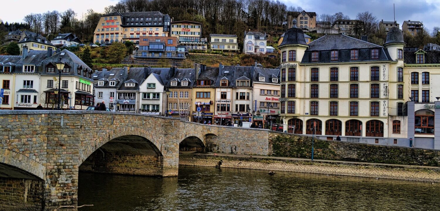 The stone bridge over the Semois at Bouillon with the town's hotels and restaurants rising up the wooded hillside behind