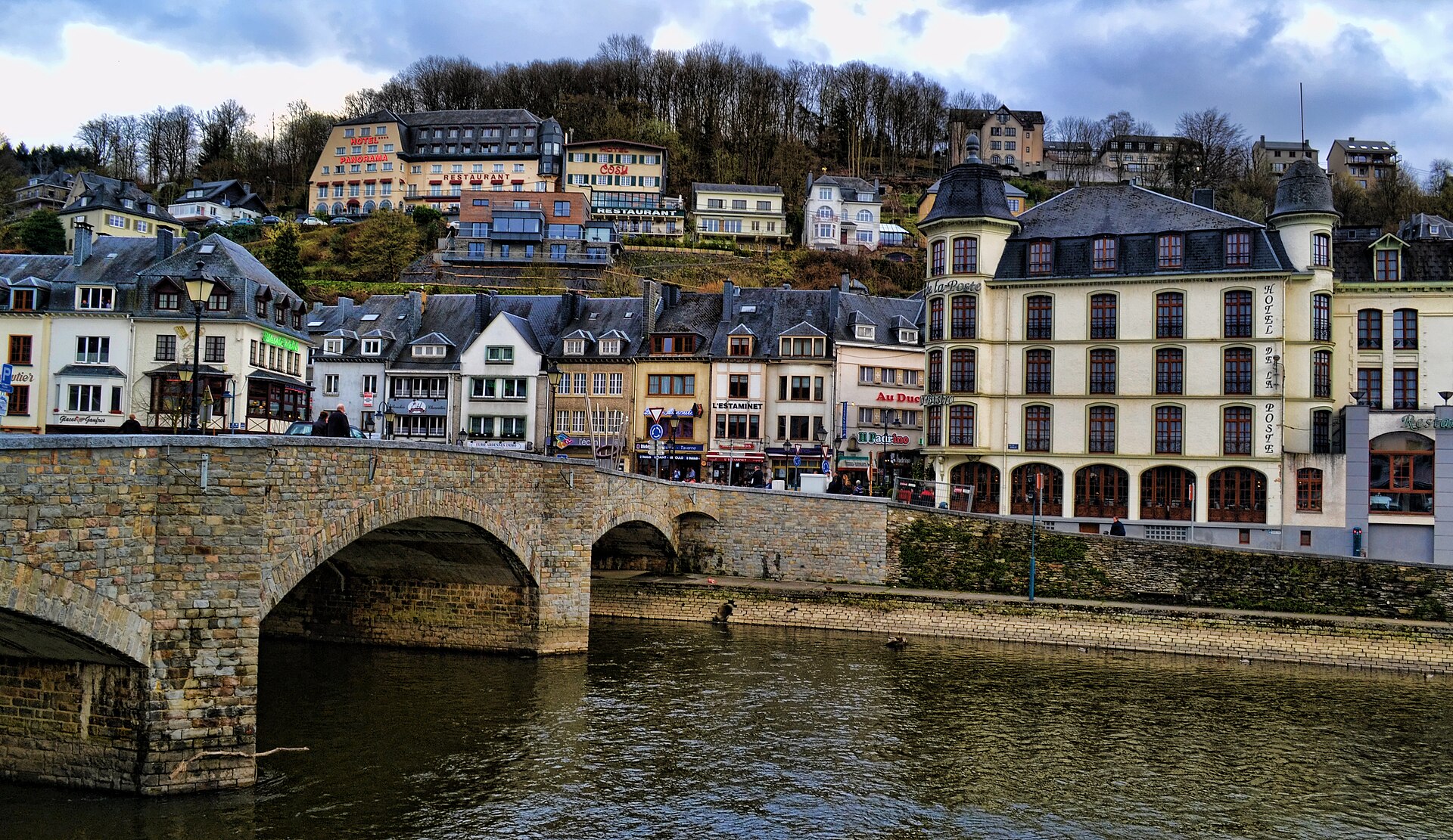 The stone bridge over the Semois at Bouillon with the town's hotels and restaurants rising up the wooded hillside behind