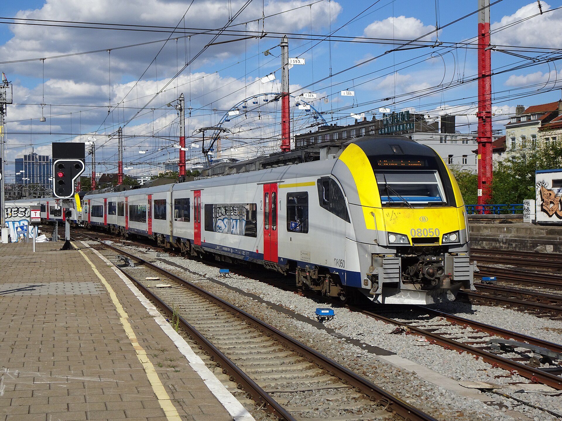 A silver and yellow Belgian Railways Desiro train standing at the open-air platforms of Brussels-Midi station