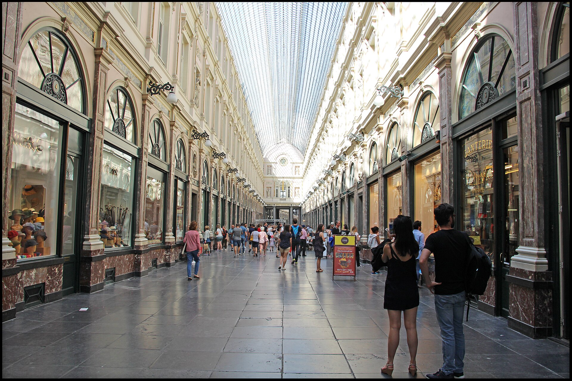 The glass-roofed Galeries Royales Saint-Hubert arcade in Brussels with shoppers walking through