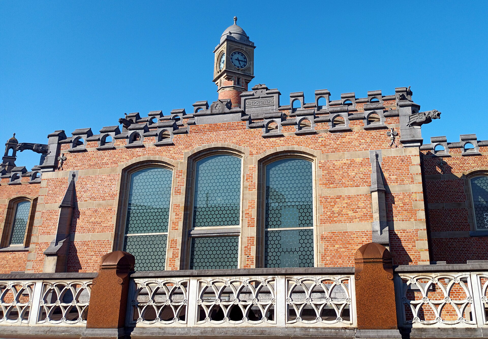 The red-brick facade of Gent-Sint-Pieters station with its clock tower, stone gargoyles and the name carved above the arched windows