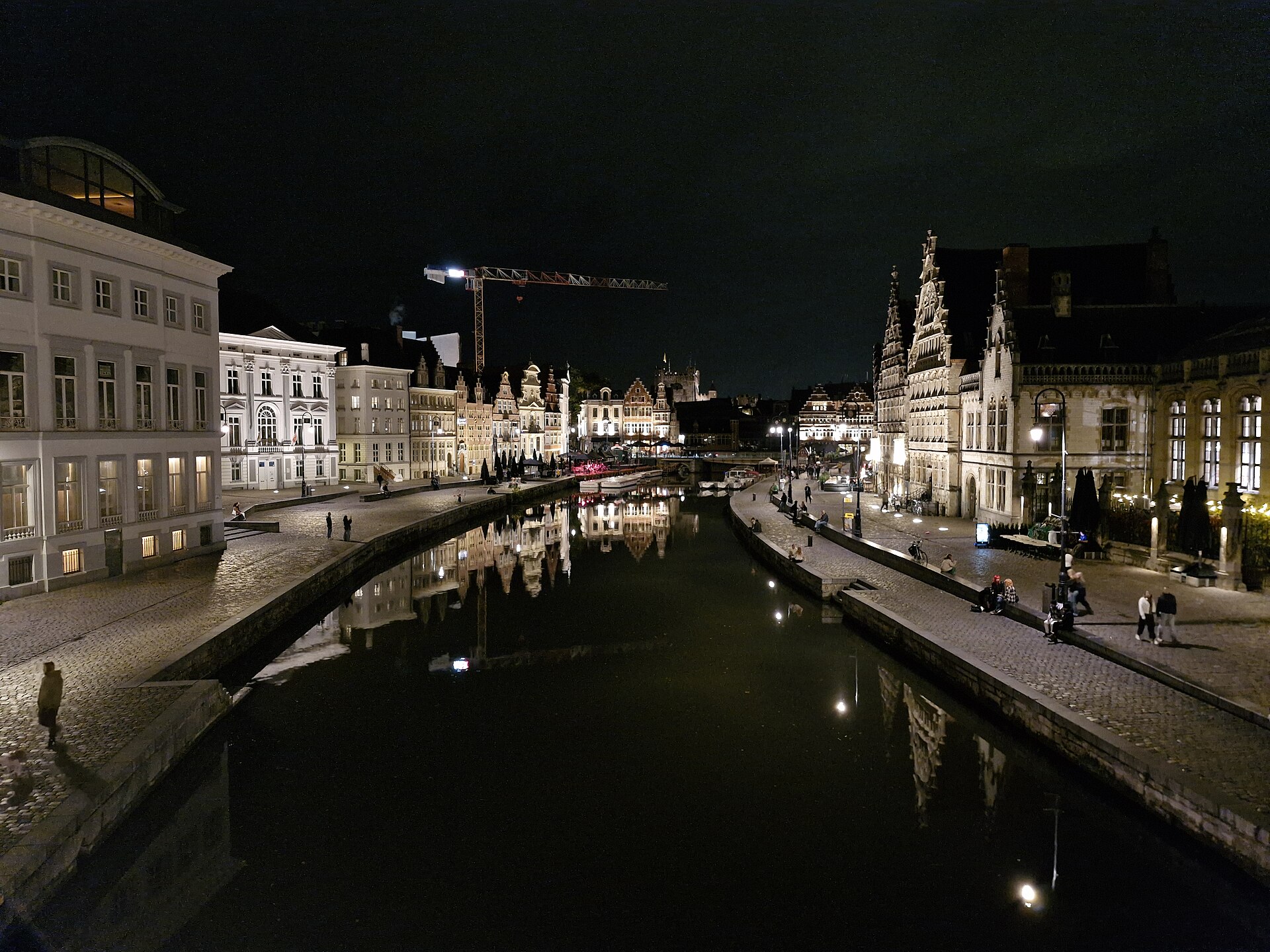 The lit guild houses of the Graslei in Ghent reflected in the river Leie at night