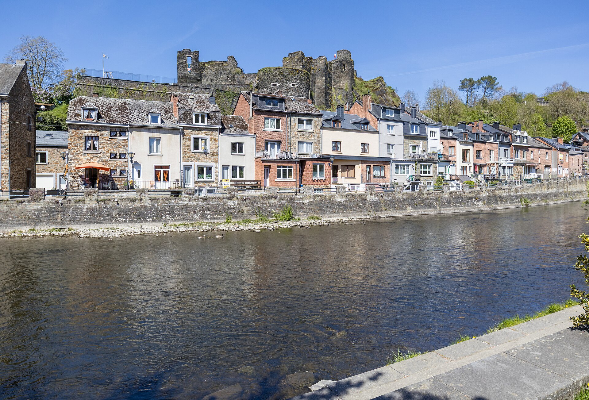 Stone and brick houses along the river Ourthe at La Roche-en-Ardenne with the ruined feudal castle on the crag above