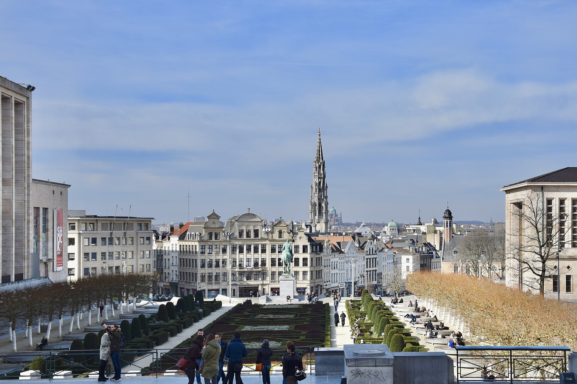 The view from the Mont des Arts over the formal garden towards the Brussels Town Hall spire, with people standing at the balustrade
