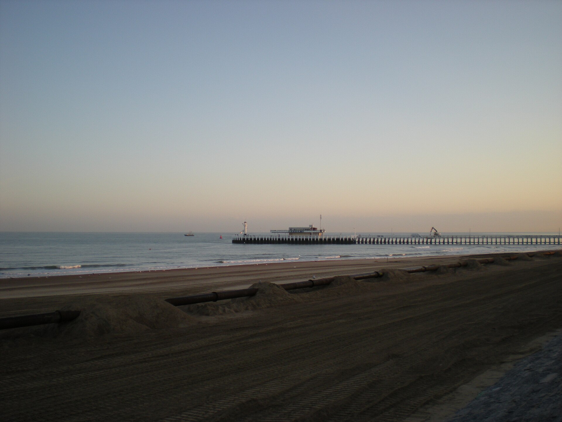 The estacade pier at Ostend at dusk with sand replenishment pipes laid along the empty beach