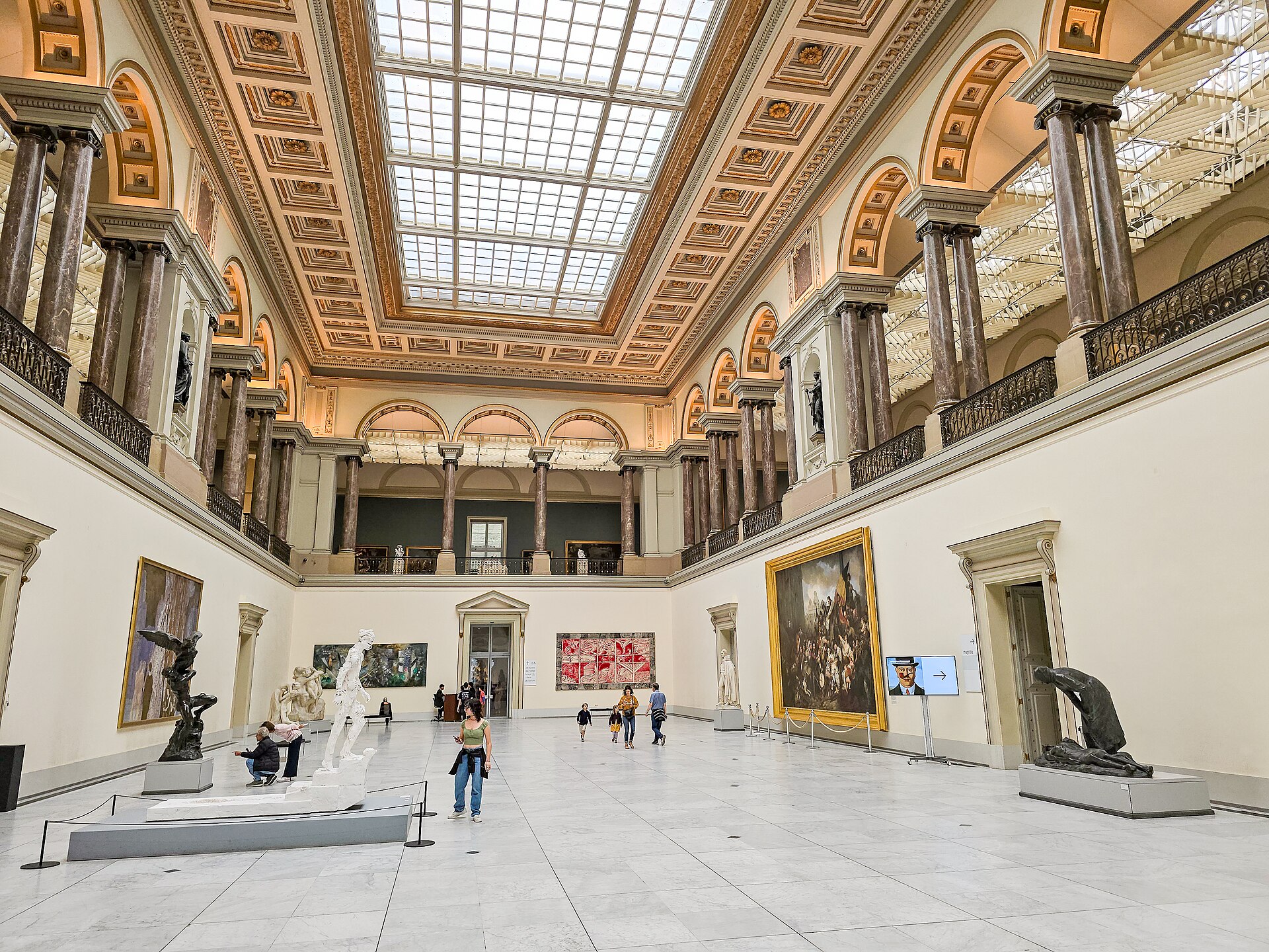 The skylit great hall of the Royal Museums of Fine Arts of Belgium, with sculptures and large paintings around a marble floor