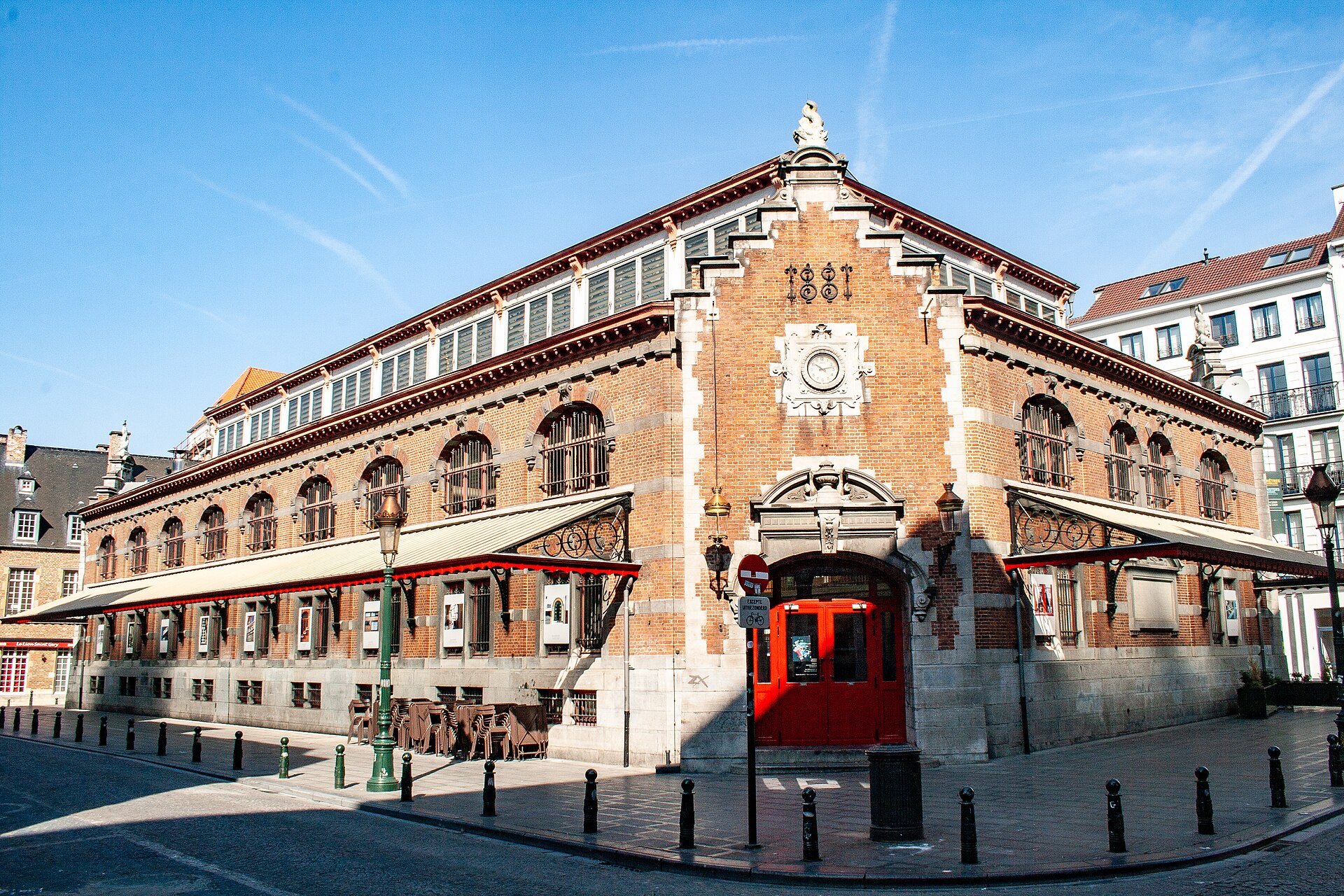 The brick Halles Saint-Gery in Brussels has arched iron windows, red entrance doors and an 1881 date above its clock.