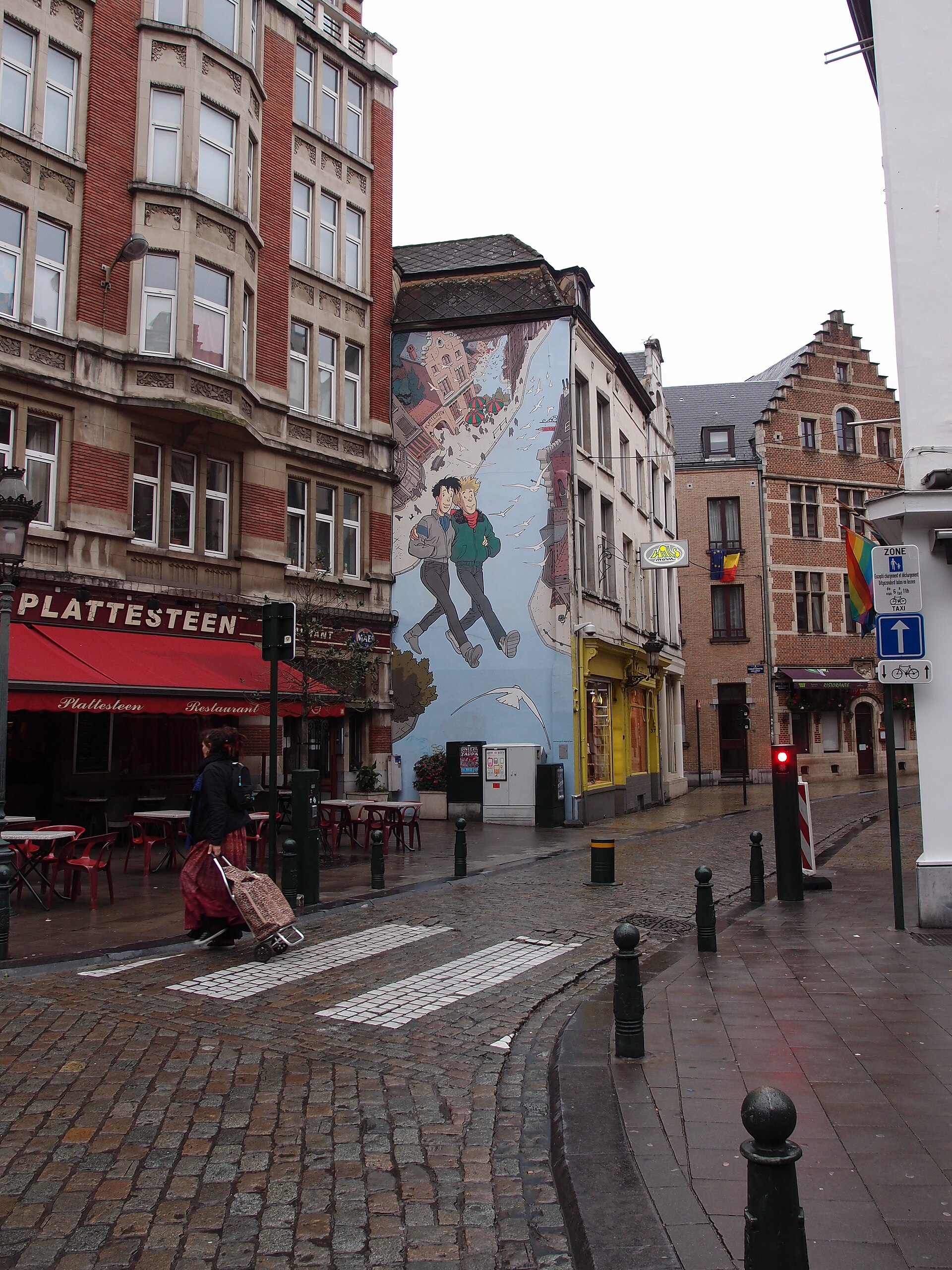 The Broussaille mural rises above restaurant terraces and a cobbled junction on Rue du Marché au Charbon in Brussels.