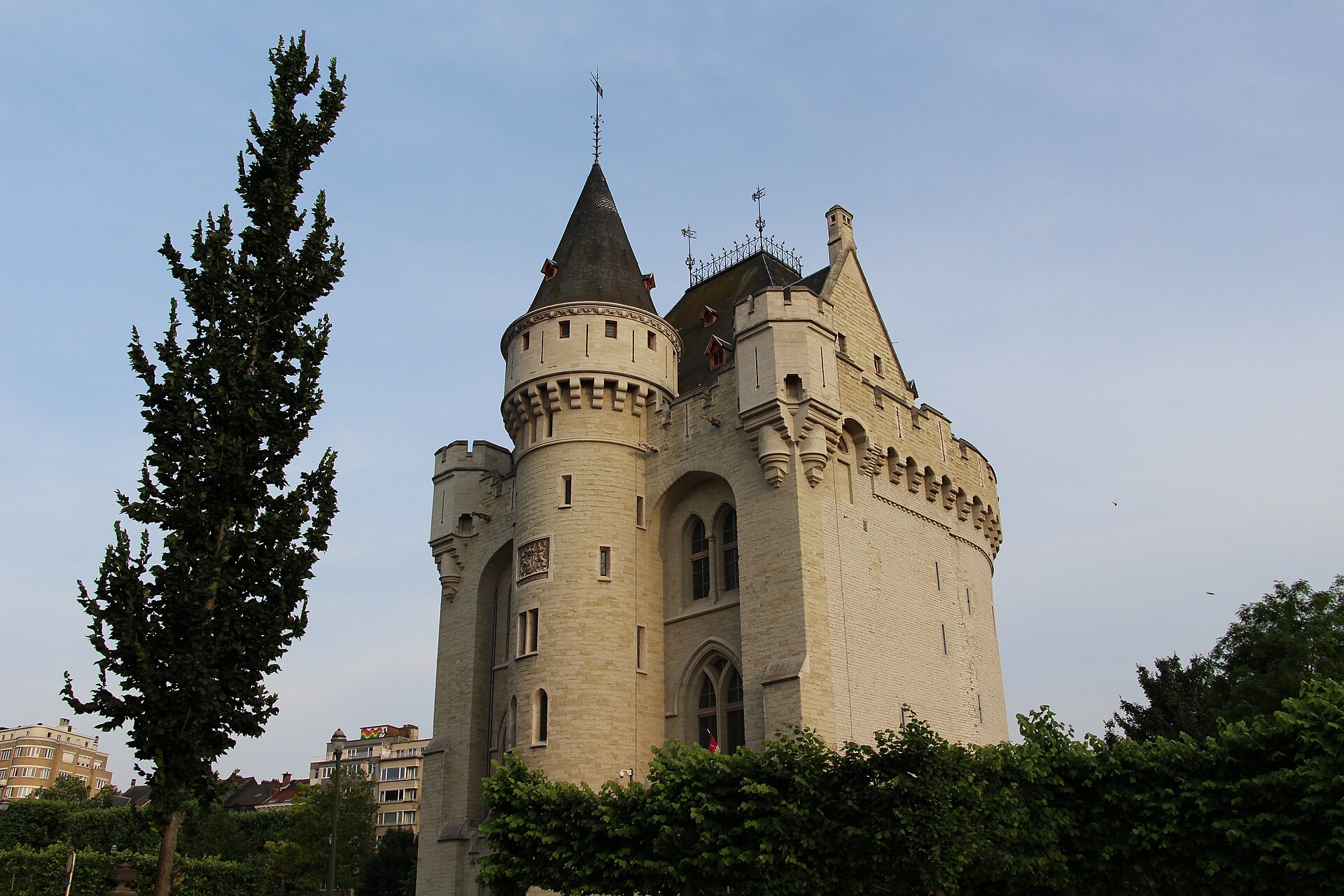 Brussels' Porte de Hal rises above park trees, with a round stair turret, battlements and a steep slate roof.
