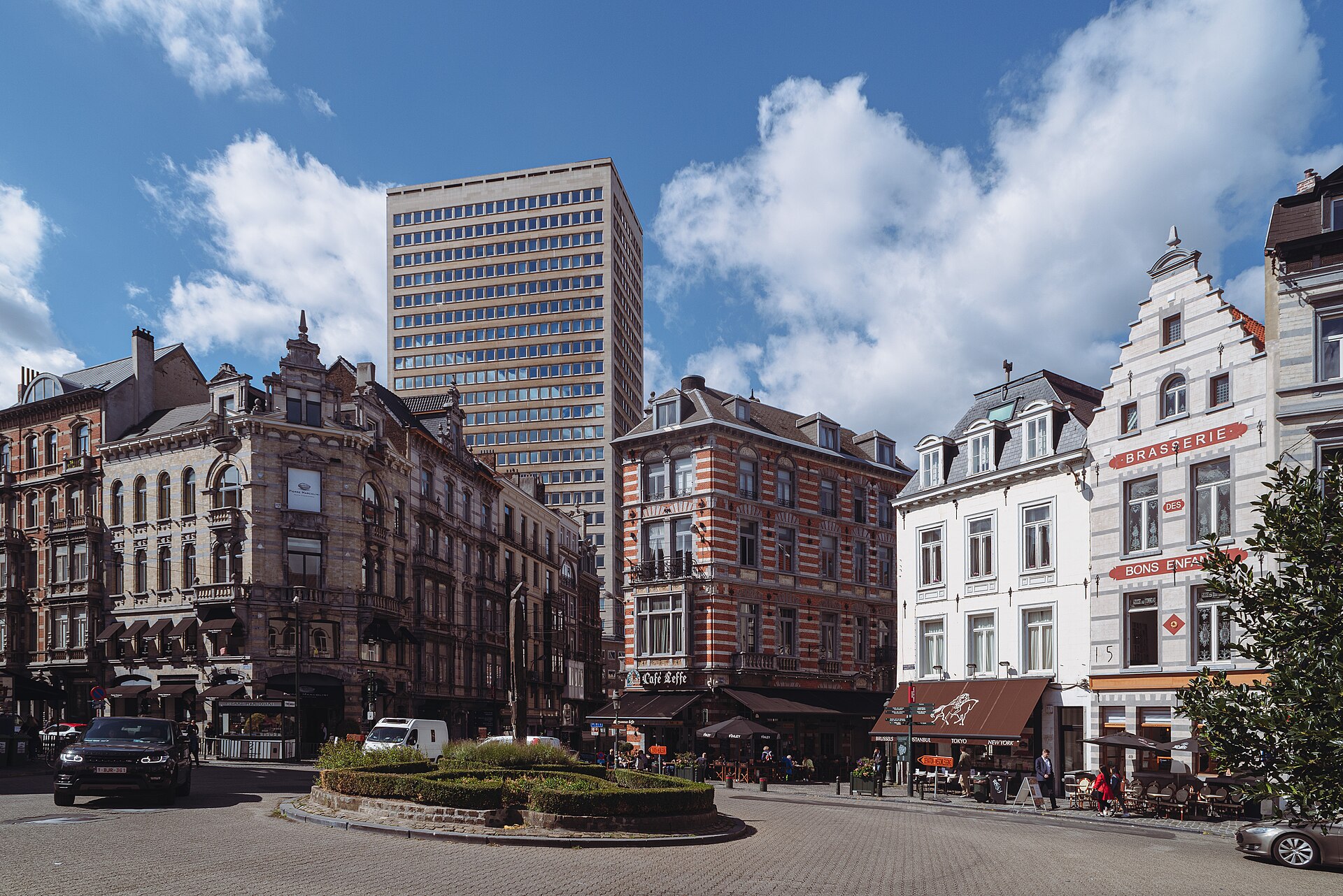Cafe terraces and stepped gables line Place du Grand Sablon in Brussels beneath a blue sky.