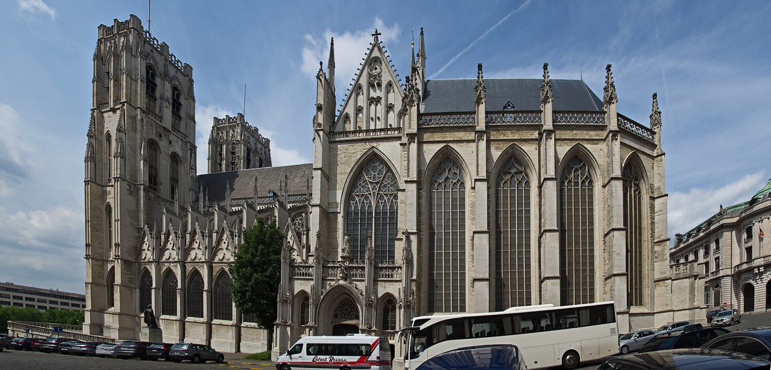 The Cathedral of St Michael and St Gudula in Brussels rises above parked coaches, showing twin towers and tall Gothic windows.
