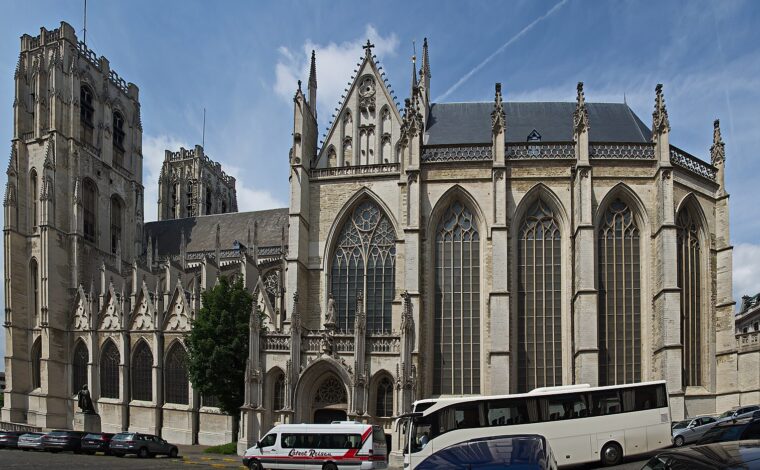 The Cathedral of St Michael and St Gudula in Brussels rises above parked coaches, showing twin towers and tall Gothic windows.