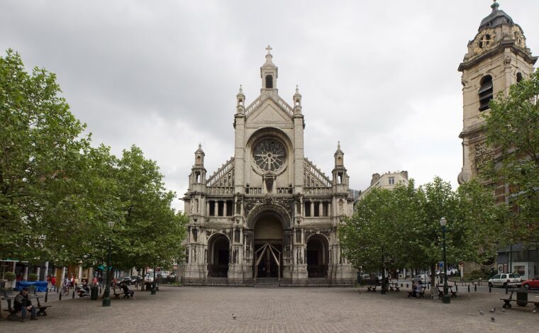 The Church of Sainte-Catherine faces a cobbled Brussels square, with leafy trees, benches and its separate clock tower at right.