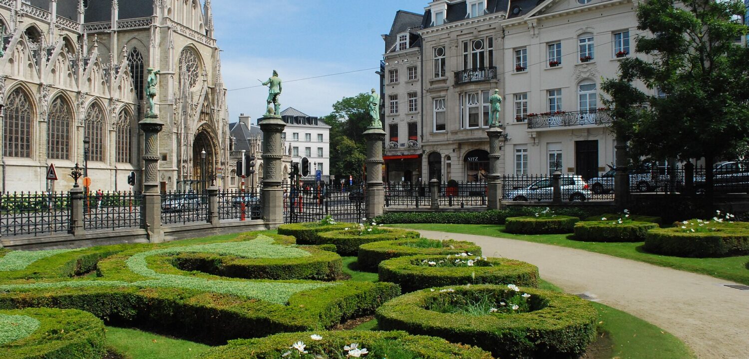 Clipped hedges and bronze statues frame Notre-Dame du Sablon across the street from the Petit Sablon garden in Brussels.