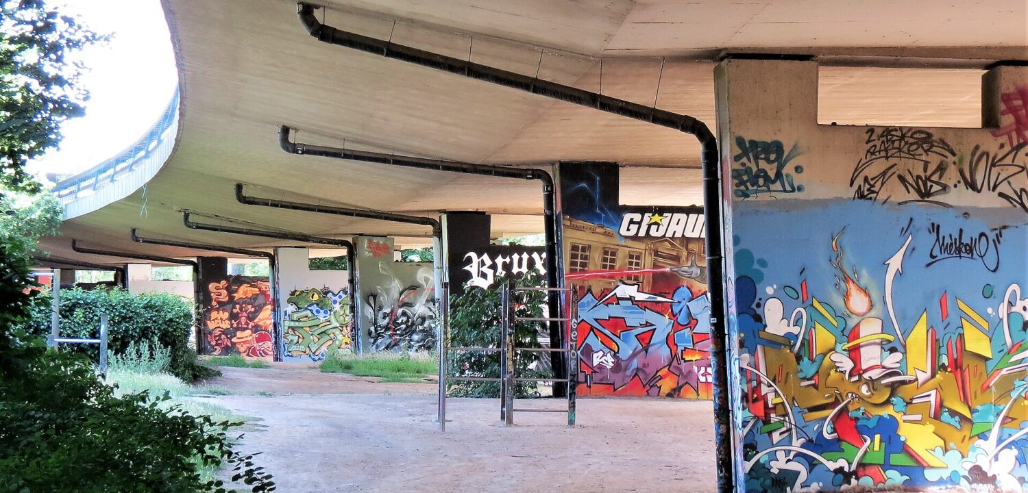 Colorful graffiti covers concrete pillars beneath a curving viaduct at the Neerpede Hall of Fame in Anderlecht, Brussels.