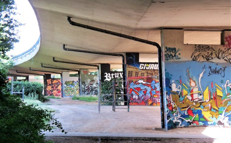 Colorful graffiti covers concrete pillars beneath a curving viaduct at the Neerpede Hall of Fame in Anderlecht, Brussels.