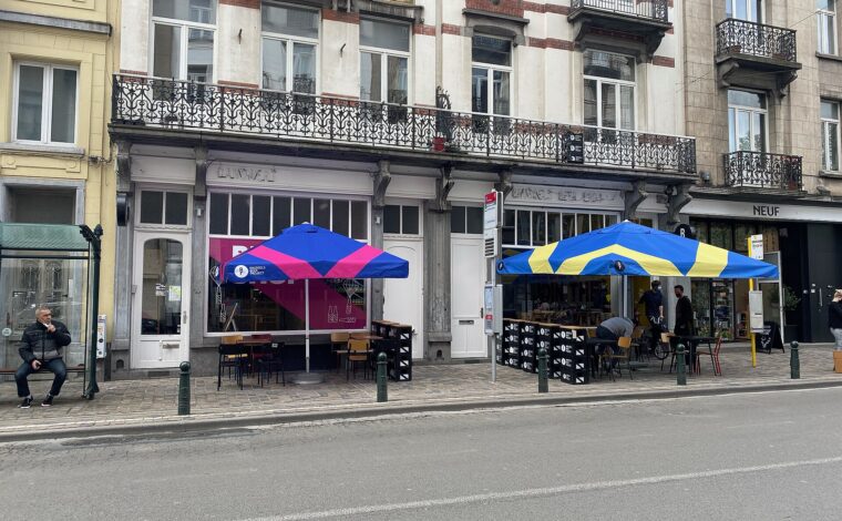 Colourful parasols shelter the Brussels Beer Project terrace on Rue Antoine Dansaert, beneath ornate balconies and tall shop windows.