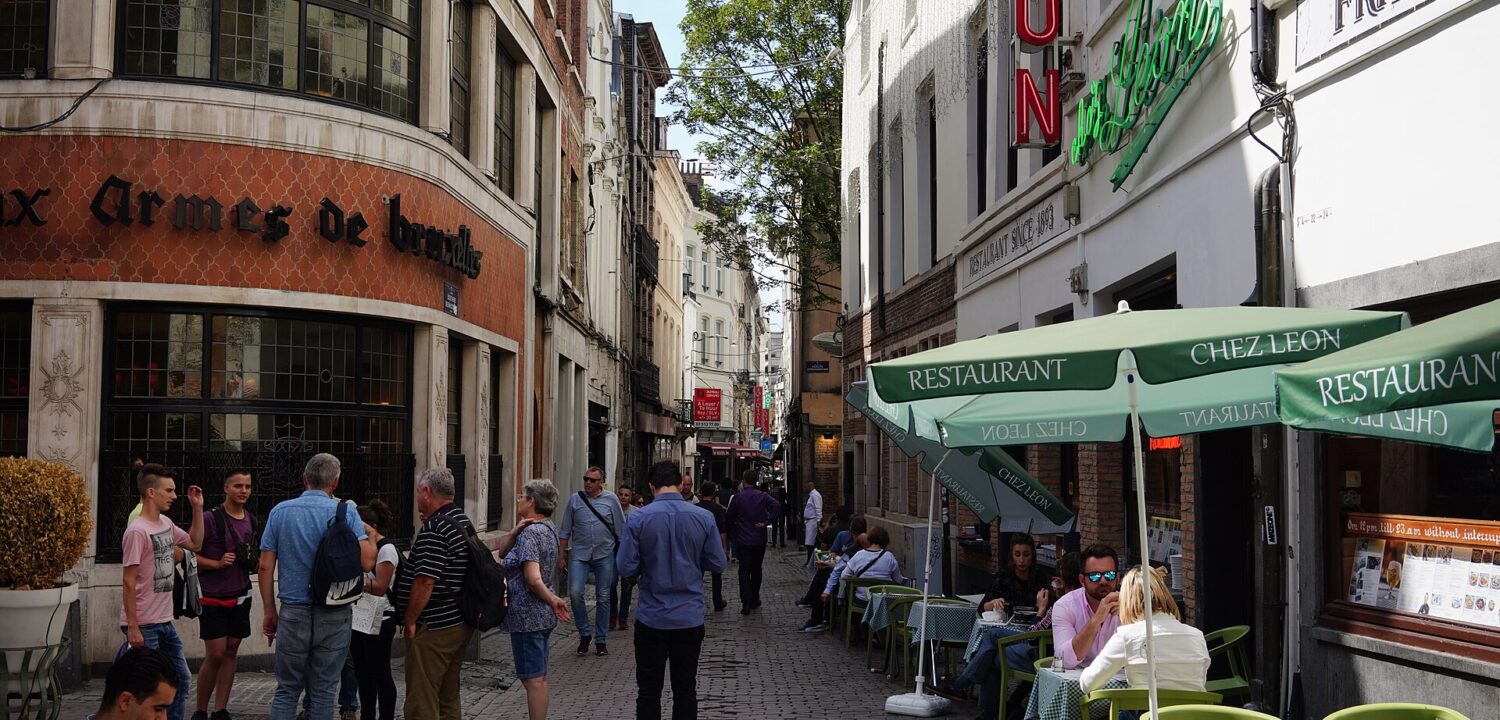 Diners sit beneath green umbrellas outside Chez Leon on Brussels Rue des Bouchers, opposite Aux Armes de Bruxelles.