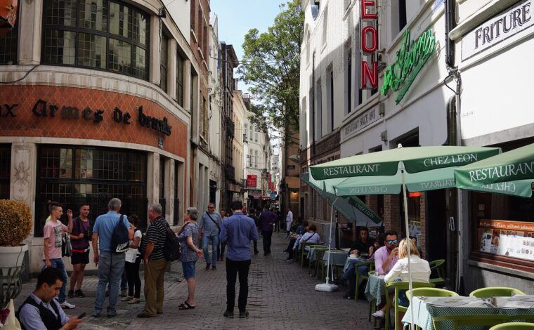 Diners sit beneath green umbrellas outside Chez Leon on Brussels Rue des Bouchers, opposite Aux Armes de Bruxelles.