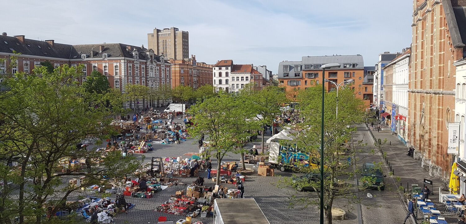 An elevated view shows secondhand stalls spread across Brussels Place du Jeu de Balle, between trees and historic buildings.