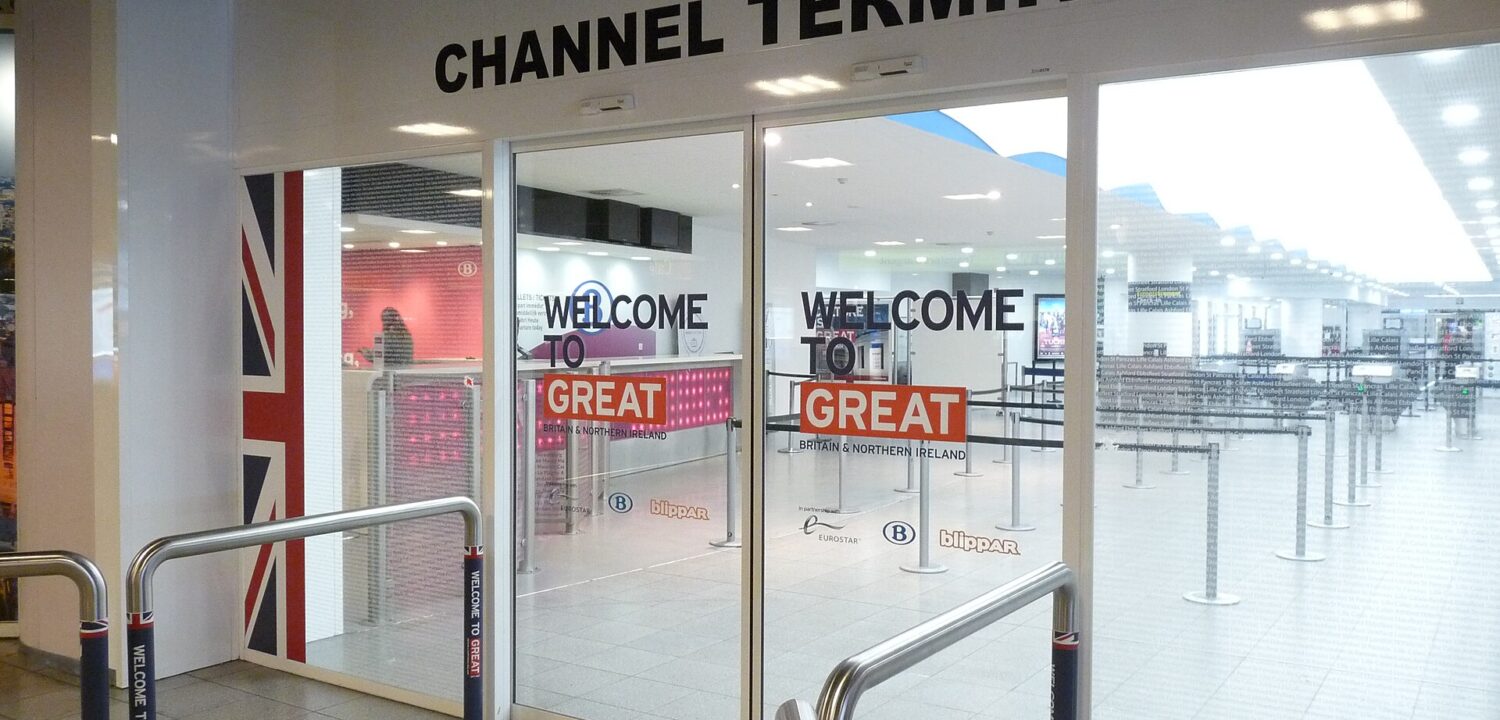 Glass doors mark the Eurostar Channel Terminal entrance at Brussels-Midi, with British flag graphics and queue barriers inside.
