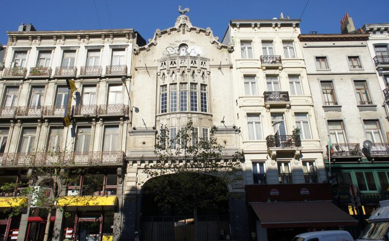 The historic Palace cinema facade in Brussels has a sculpted central window bay and a rooster crowning its gable.