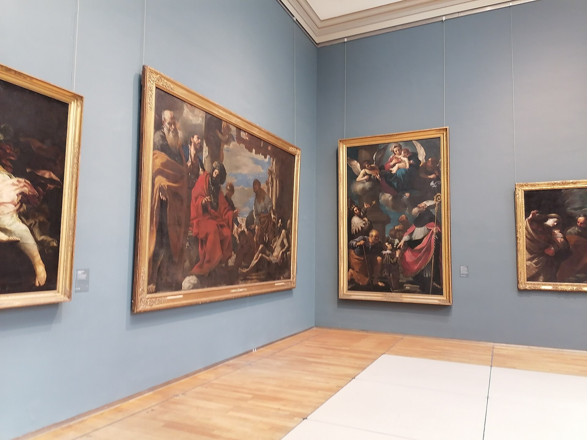 Large religious paintings in gold frames hang on blue walls inside the Royal Museums of Fine Arts of Belgium in Brussels.