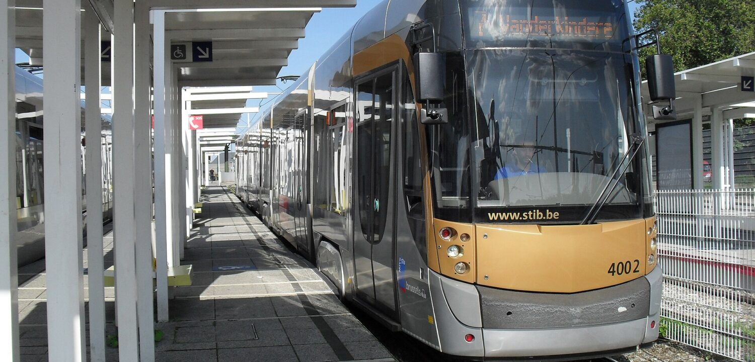 A low-floor STIB tram waits beside Heysel’s covered platform in Brussels, with wheelchair signs marking the boarding area.