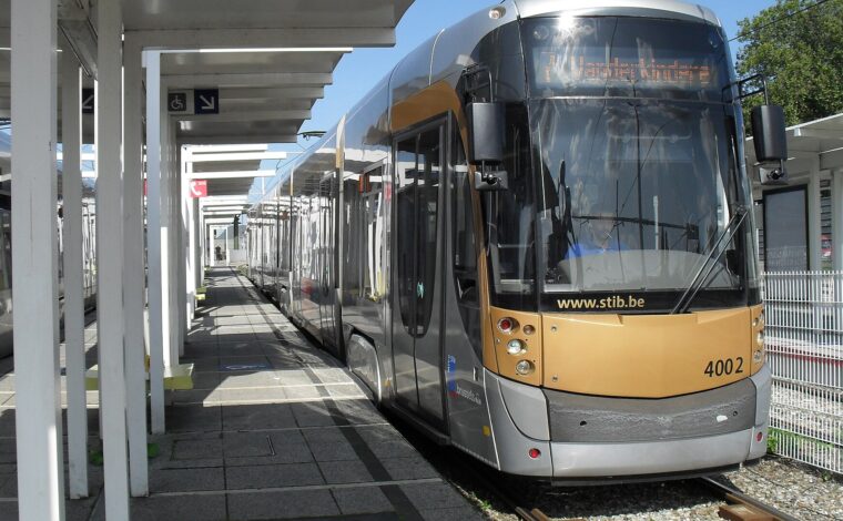 A low-floor STIB tram waits beside Heysel’s covered platform in Brussels, with wheelchair signs marking the boarding area.