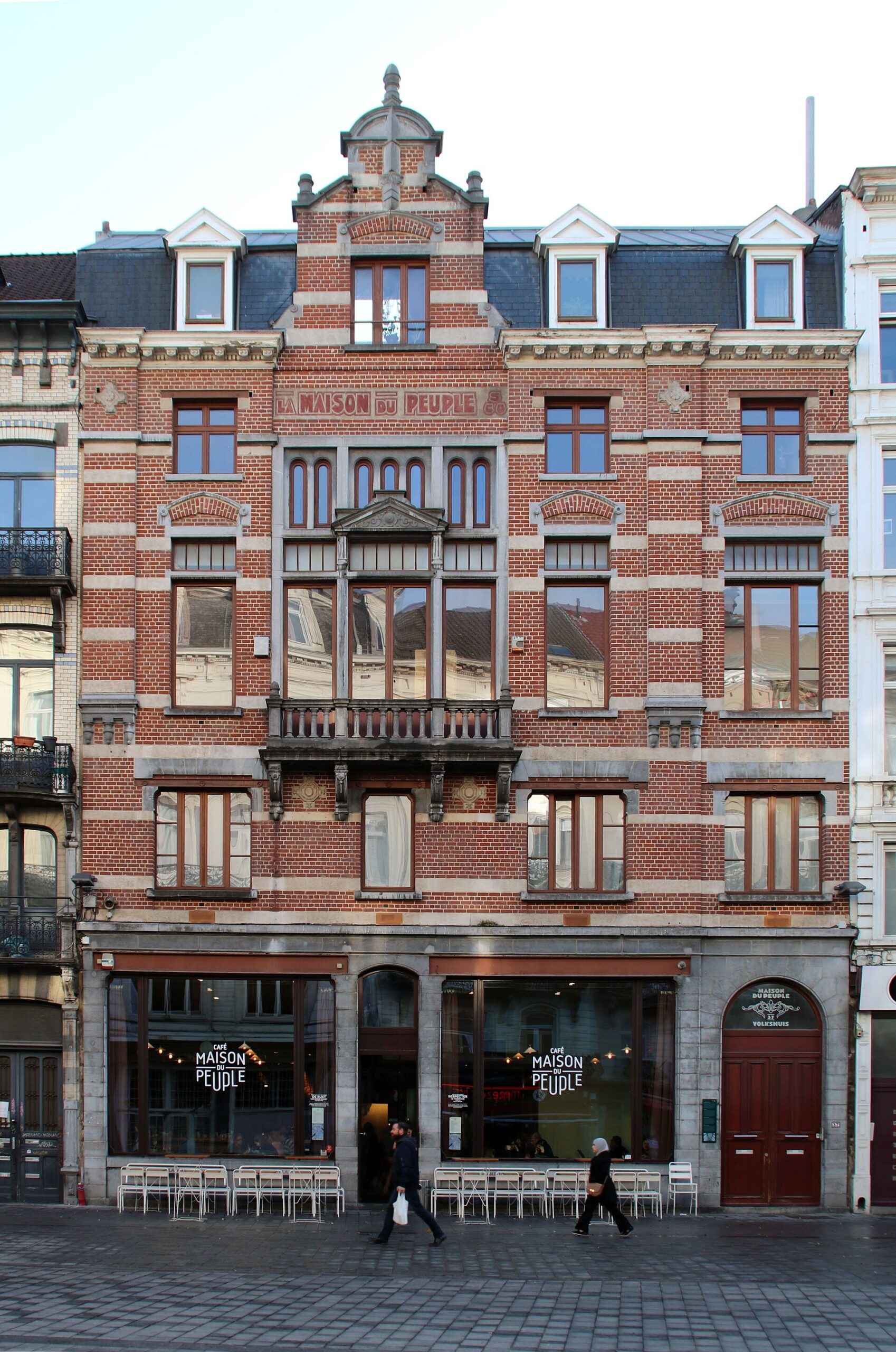 Maison du Peuple cafe on the Parvis de Saint-Gilles in Brussels, with red brickwork, tall windows and pedestrians outside.
