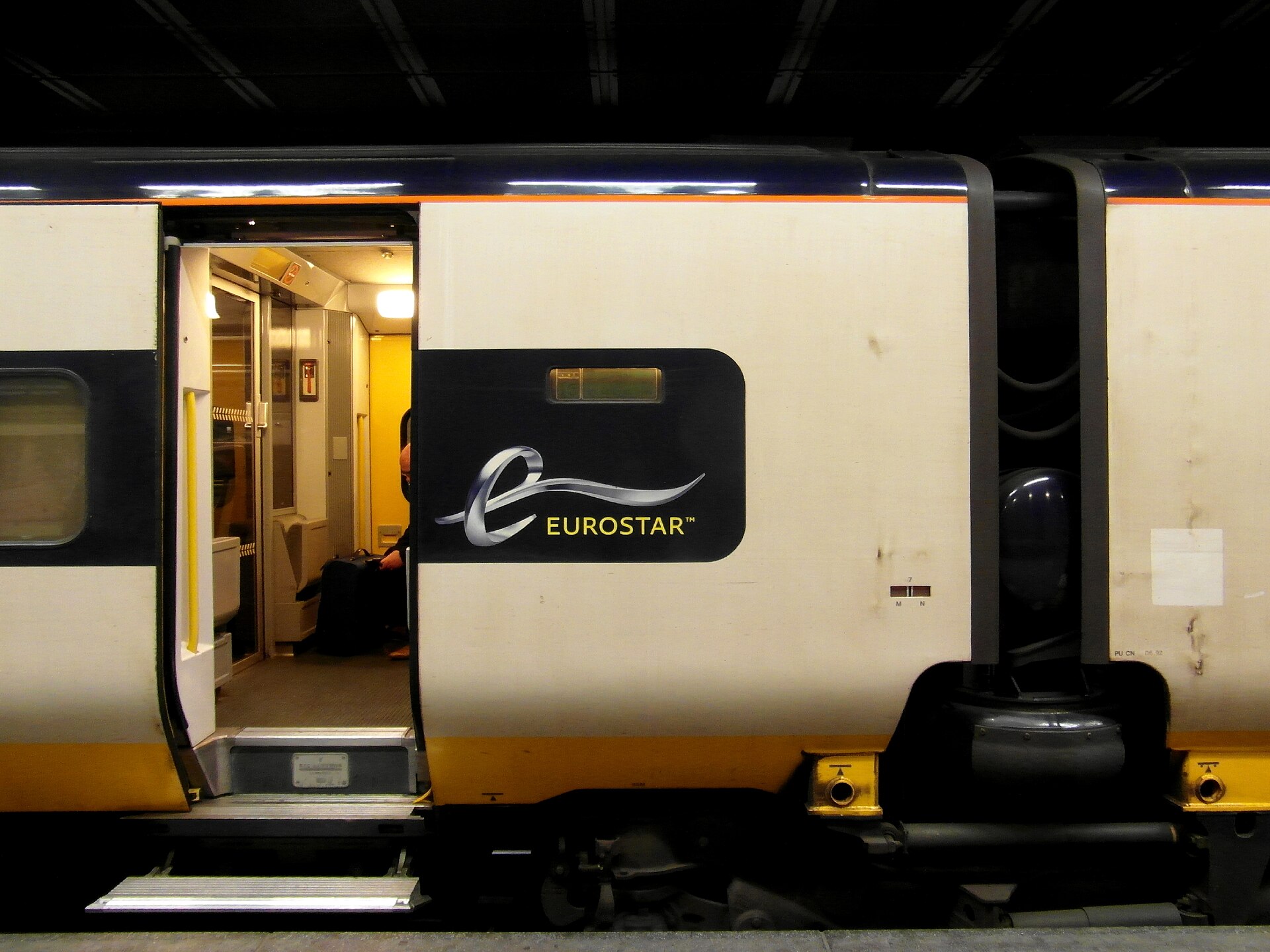 An open doorway and boarding steps sit beside the Eurostar logo on a train at Brussels-Midi station.