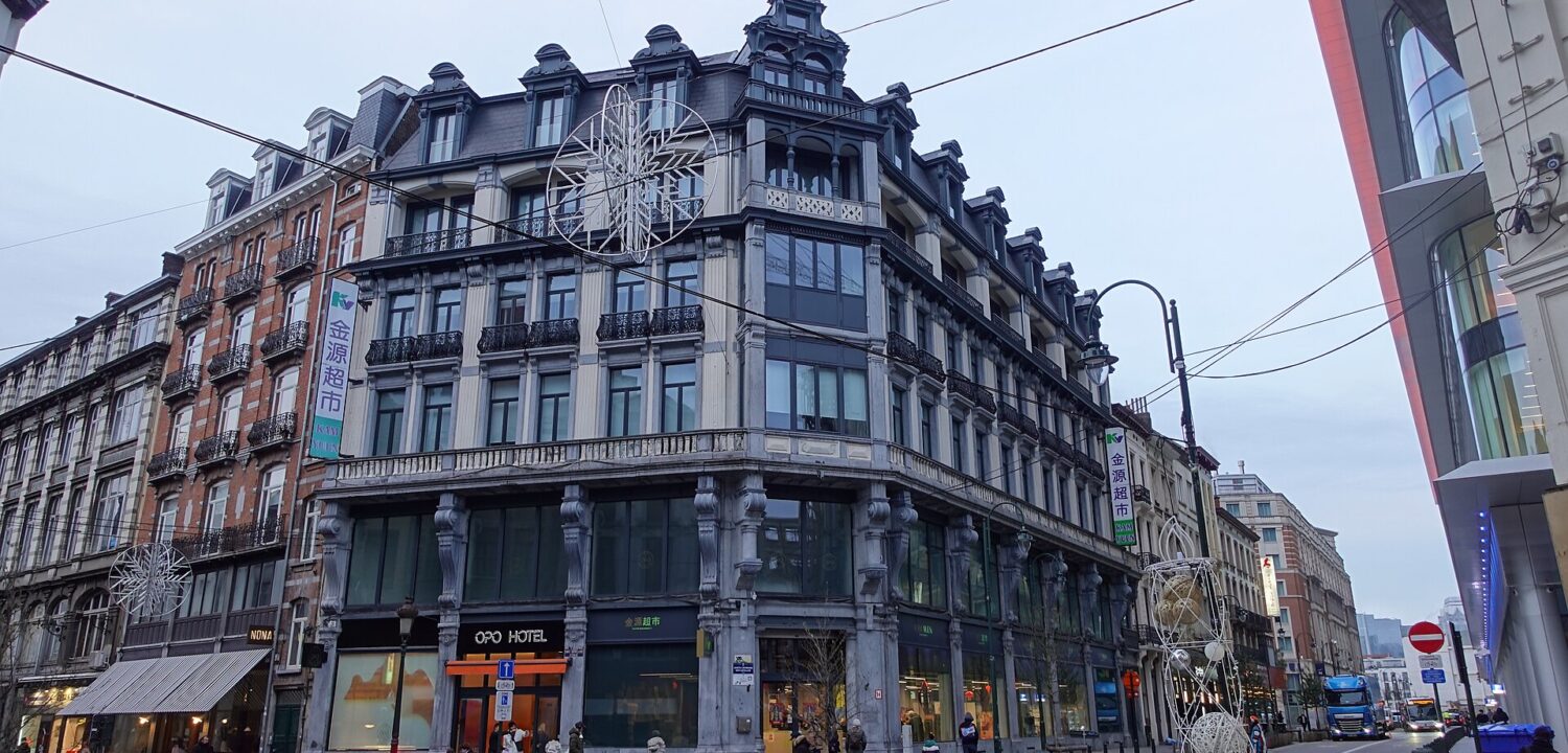 The OPO Hotel occupies an ornate corner building in Brussels, with balconies, tall windows and pedestrians outside its entrance.