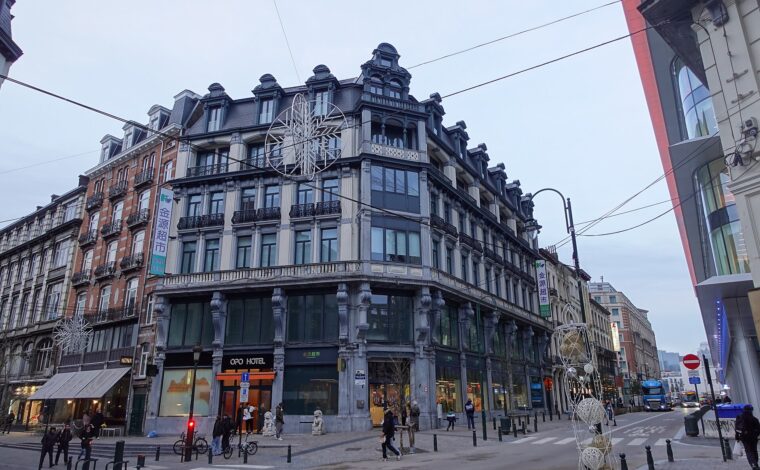 The OPO Hotel occupies an ornate corner building in Brussels, with balconies, tall windows and pedestrians outside its entrance.
