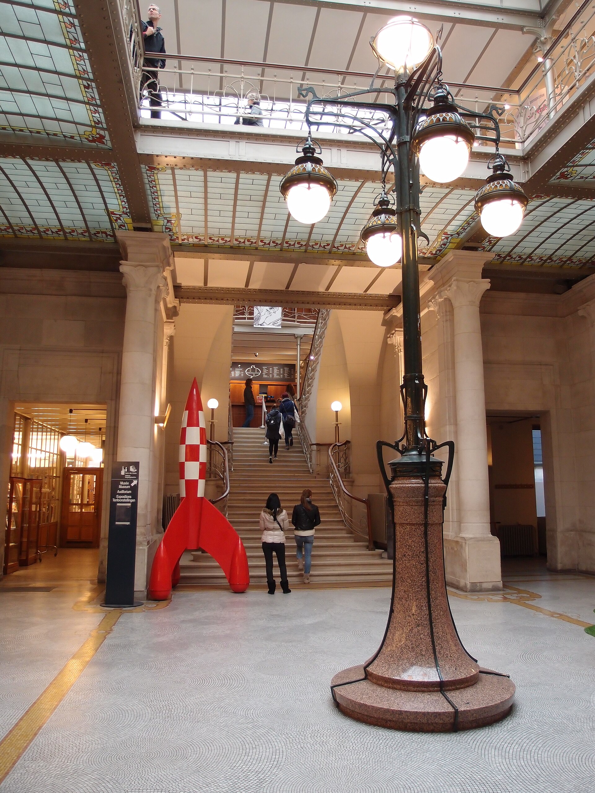 A red and white Tintin rocket stands beside visitors on the staircase inside the Belgian Comic Strip Centre in Brussels.