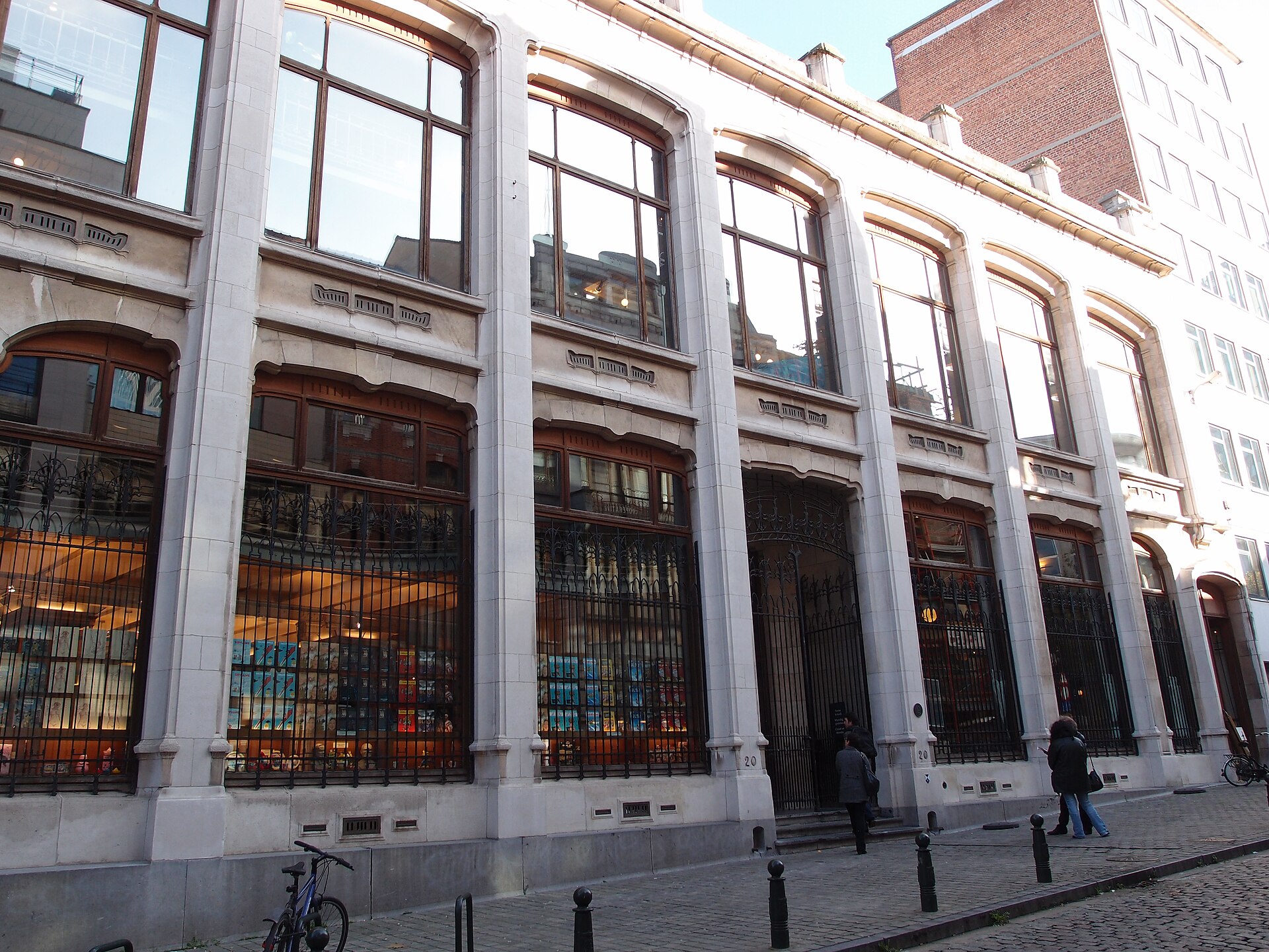 Tall windows and decorative iron grilles line the Belgian Comic Strip Centre facade as visitors approach its Brussels entrance.
